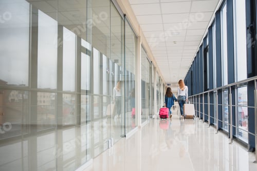 Preview: Happy young mother and her daughter walking in the airport terminal