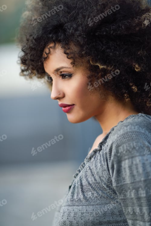 Preview: Young black woman with afro hairstyle smiling in urban backgroun