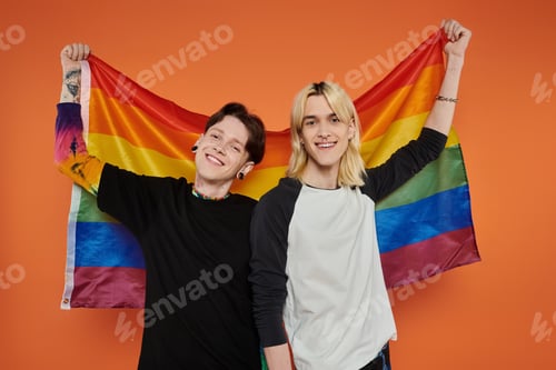 Preview: Friends holding pride flag against orange background