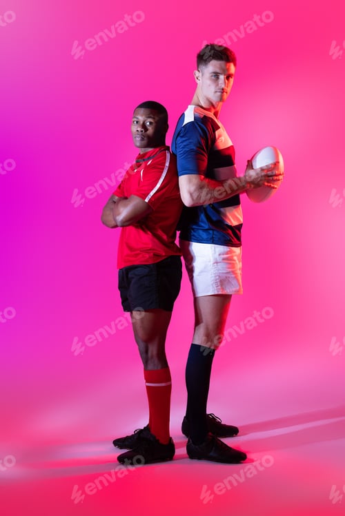Preview: Portrait of diverse male rugby players with rugby ball over pink lighting