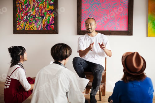 Preview: Group of Japanese men and women sitting in art gallery, holding a discussion.