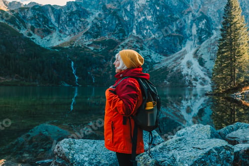 Preview: Senior 50s tourist woman with a backpack standing on top of the mountain and enjoy the beautiful