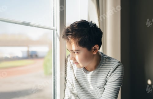 Preview: Boy Looking Out Window With Natural Light