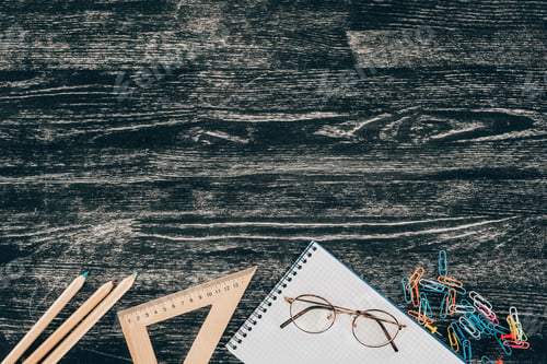 Preview: Top view of composition of colorful school supplies with blank notebook on board background