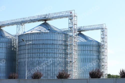 Preview: View of grain elevator against blue sky on sunny day. Cereal farming