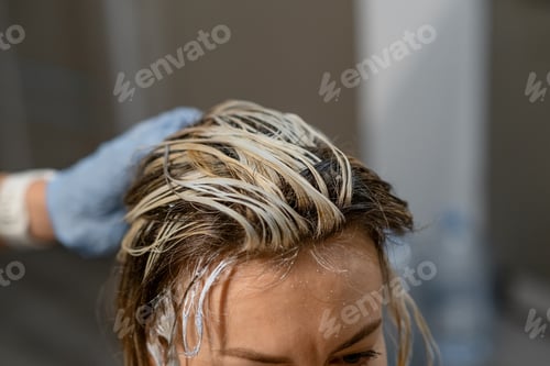 Preview: Hair coloring process with a stylist applying bleach to a clients roots in a modern salon setting