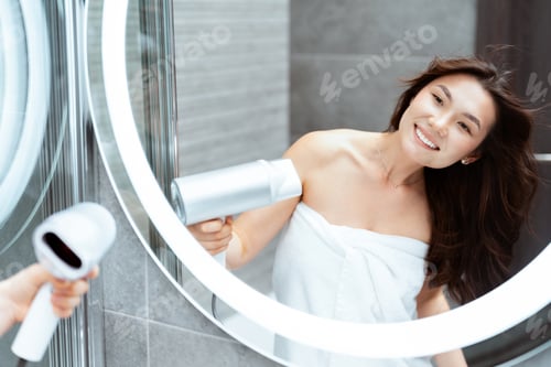 Preview: Happy Young Woman Drying Hair With Blow Dryer In Bathroom