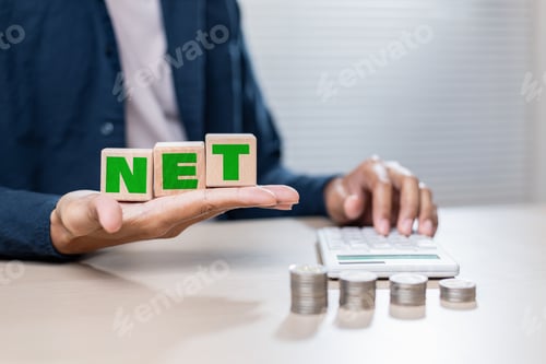 Preview: Wooden blocks spelling NET held by person near calculator and coins