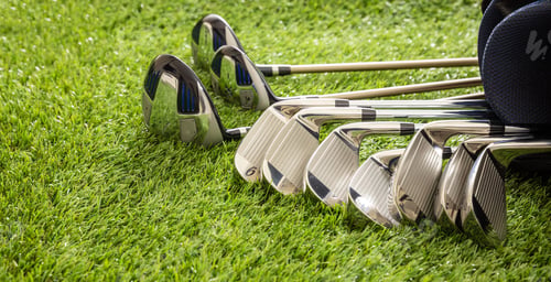 Preview: Golf clubs on green grass golf course, close up view.