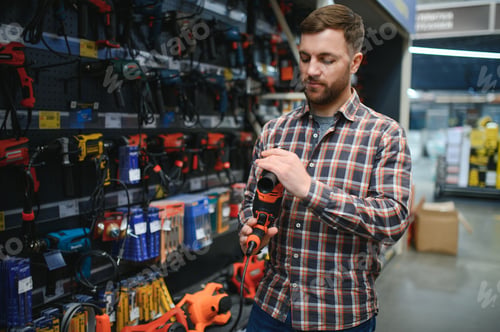 Preview: handsome young man shopping for tools at hardware store