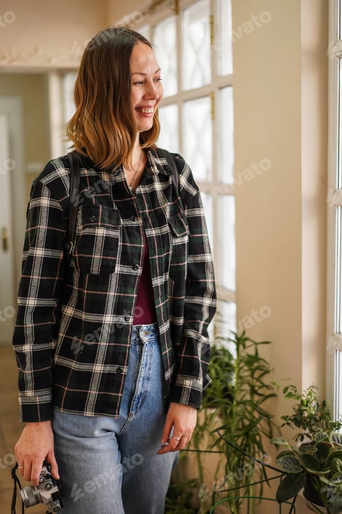 Preview: Smiling Woman with Camera Posing Indoors by Window