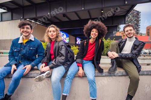 Preview: Group of four people friends tourist multiethnic sitting outdoor looking camera smiling