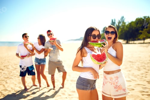 Preview: Group of friends having fun eating watermelon on beach. Excellent sunny weather. Super mood. Summer.