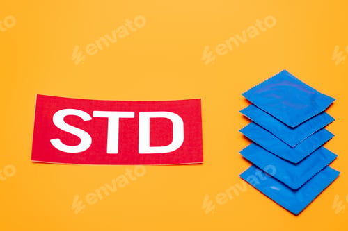 Preview: blue packs with condoms near std lettering isolated on orange