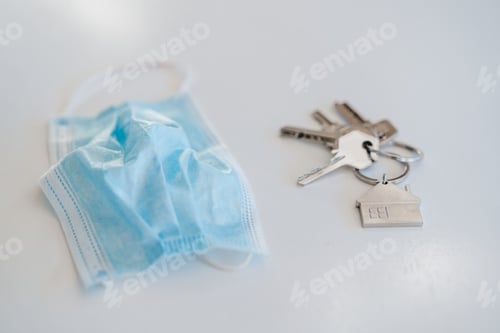 Preview: blue protective mask, keyring and keys with on table at home. Nobody. Corona virus and pandemic