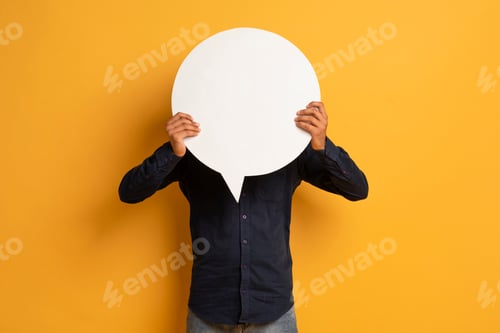 Preview: Unrecognizable young man in black shirt hiding face behind empty speech bubble