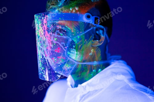 Preview: Portrait of man doctor in protective clothes in ultraviolet neon light during coronavirus pandemic