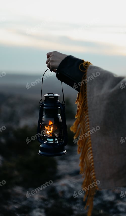 Preview: female hands holding a burning kerosene lamp