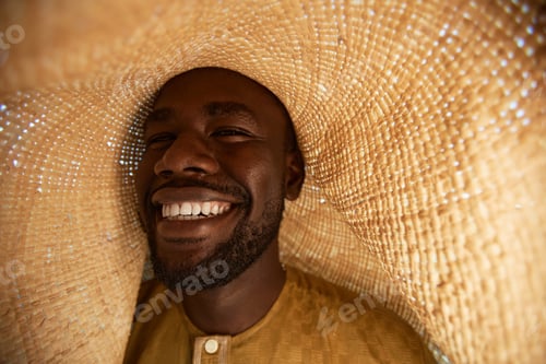 Preview: Smiling African American Man in Straw Hat Laughing Happily Outdoors