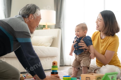 Preview: A tiny child cheerfully plays with toys on the floor of the living room with mom and grandfather