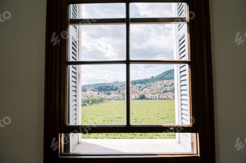 Preview: View from the window of green vineyards and a settlement at the foot of the mountains
