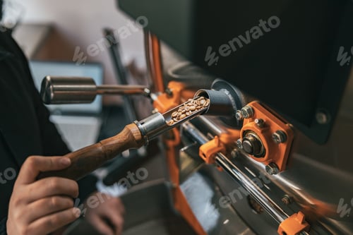 Preview: Close up of business owner hands operating modern coffee bean roasting machine