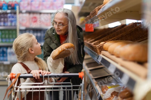 Preview: Grandmother with her granddaughter buying bread in supermarket.