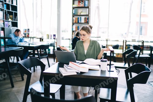Preview: Surprised student sitting and focusing on laptop at library