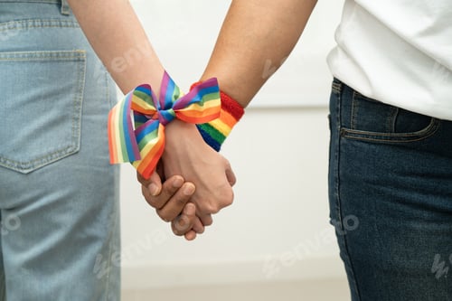 Preview: Asian LGBT couple woman holding hand wearing rainbow wristband.