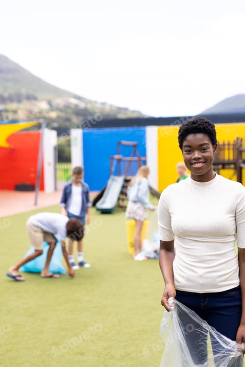 Preview: Vertical portrait of happy african american female teacher recycling in schoolyard, copy space