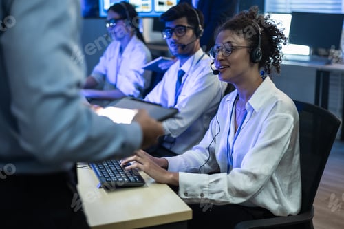 Preview: Diverse team of customer support agents with headsets working in a high-tech call center.