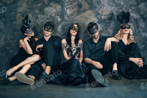 Preview: Group of friends in masquerade carnival mask sitting on floor relax after party