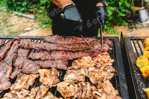 Preview: cook preparing grilled meat during a barbecue.