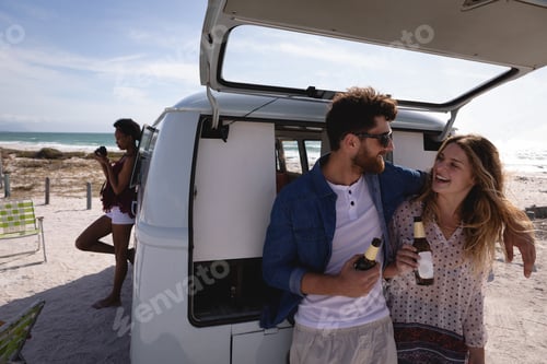 Preview: Couple interacting with each other while having beer at beach