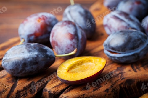 Preview: Fresh organic plums on rustic wooden cutting board