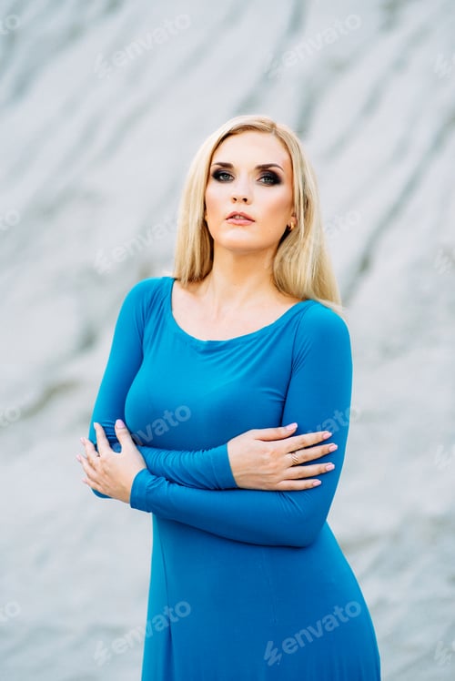 Preview: blonde girl in a blue dress with blue eyes in a granite quarry