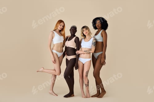 Preview: Happy multicultural girls wearing underwear standing on beige background.