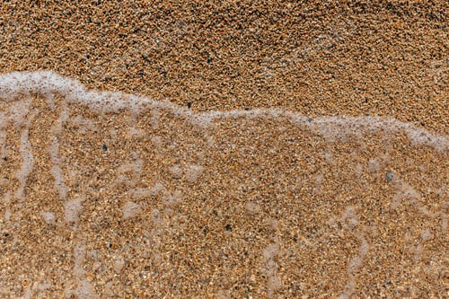Preview: Closeup detail of the foaming sea waves washing ashore at the beach.