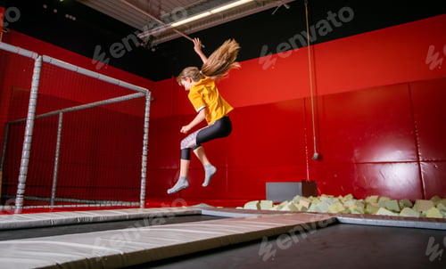 Preview: Happy fit child girl jumping on trampoline in fitness center