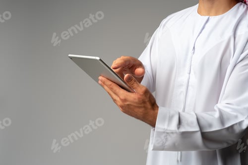 Preview: Close up of Arab man holding digital tablet on gray background