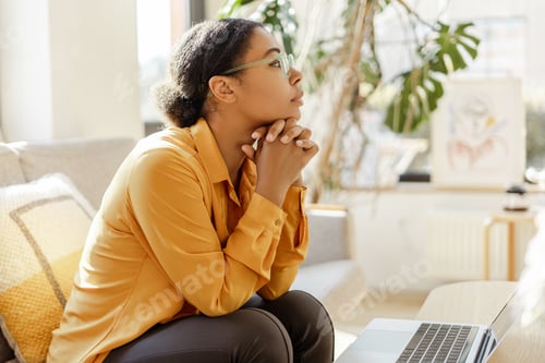 Preview: Thoughtful African American business woman, freelancer pondering while working laptop