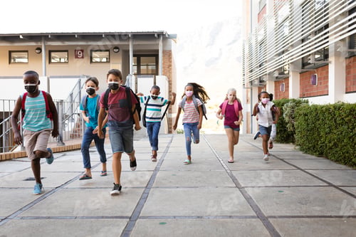Preview: Group of diverse students wearing face masks running at elementary school