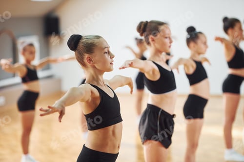 Preview: Side view of group of female kids that practicing athletic exercises together indoors