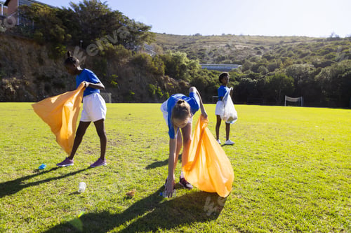Preview: In school, diverse girls picking up trash on field, participating in cleanup activity