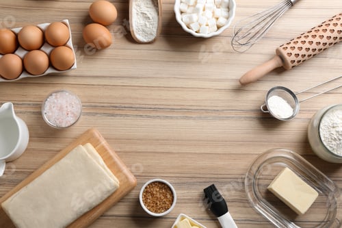 Preview: Frame made with puff pastry dough and ingredients on wooden table, flat lay. Space for text