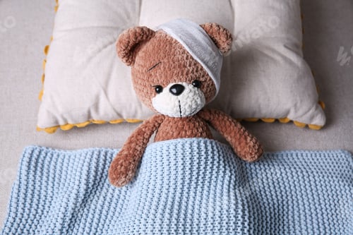 Preview: Cute toy bear with bandage in bed. Children's hospital