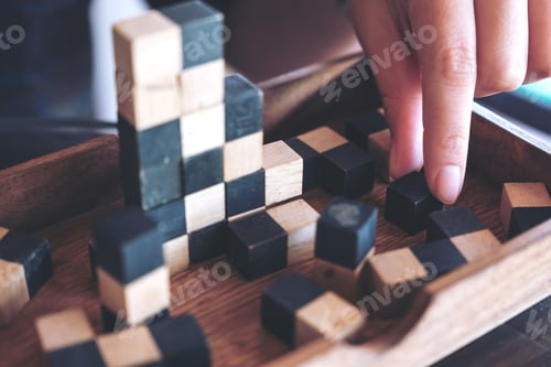Preview: Closeup image of people playing and building wooden puzzle game