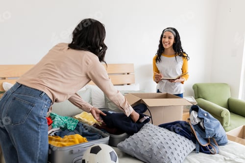 Preview: Mother and daughter packing suitcase and boxes, preparing for trip together