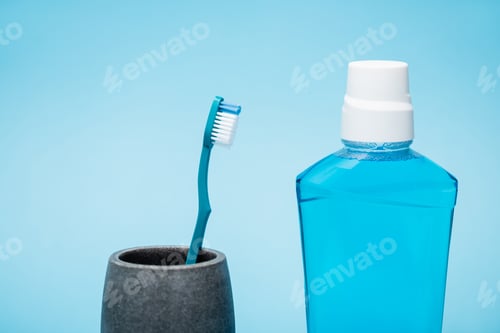 Toothbrush and bottle of mouthwash on blue background