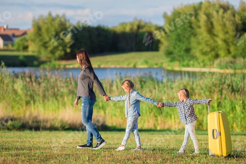 Preview: Happy family with suitcase walking outdoors